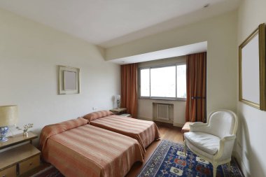 Bedroom with twin beds with old bedspreads, a white wooden armchair and blue carpet