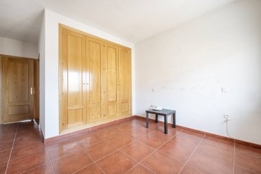 Room with red stoneware floors with a black bedside table, a built-in wardrobe with four oak doors and an access door made of the same material