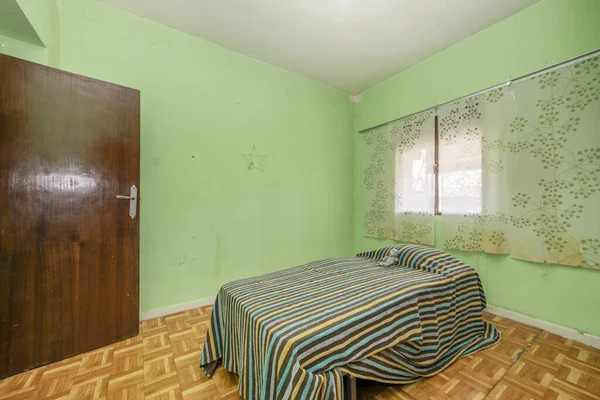 Room with sintasol floor, old cheap door, green walls and dirty curtains