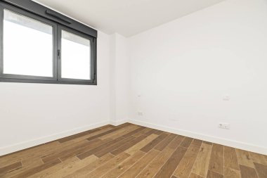 Empty room with dark wood-effect stoneware floors, two-leaf black aluminum windows with blinds and smooth white painted walls