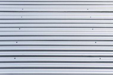 A surface of corrugated metal material with fastening screws