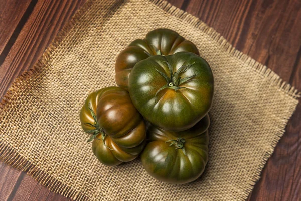 Image of delicious sweet jam tomatoes on brown burlap cloth and everything else on a wooden table