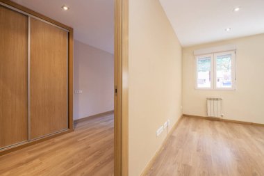 Empty rooms with laminate parquet flooring, built-in wardrobe with sliding doors and white aluminum windows