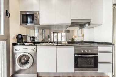 Kitchen front of vacation apartment with gray cabinets, stainless steel appliances and mirror on the wall