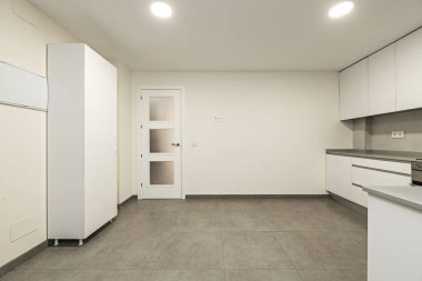 apartment kitchen with white cabinets, built-in stainless steel appliances, gray stone countertop, and gray tile kitchen walls and flooring