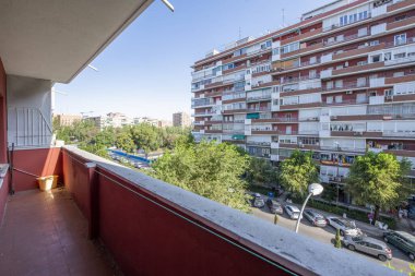 long narrow terrace with red paint and views of a street lined with trees and other buildings
