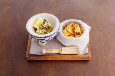 presentation of a plate of guacamole with corn tortilla chips on a porcelain molcajete