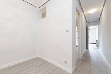 Distribution corridors of an empty house with light oak flooring, smooth white walls and white carpentry on doors and skirting boards