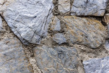 Wall with disparate slate stones joined with cement mortar between the joints