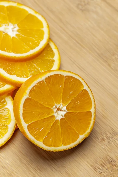 Slices of ripe oranges and a half orange on a bamboo wooden kitchen board