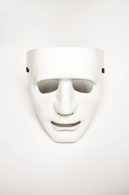 An expressionless mask of white color on a smooth white surface