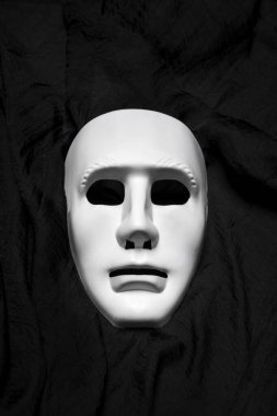 Expressionless white masks on a black cloth