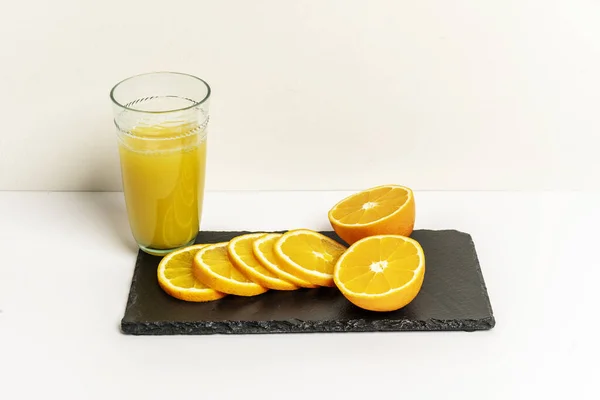 A glass of fresh orange juice along with sliced oranges