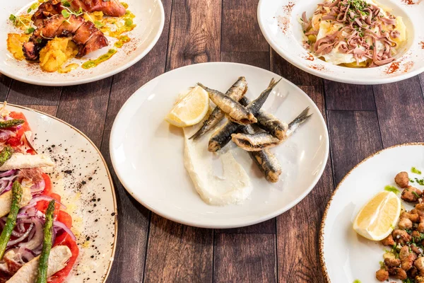 Set of dishes with Spanish tapas recipes with fried anchovies, grilled octopus, ventresca salad and criadillas