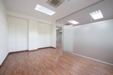 Empty office with technical ceilings, white walls with friezes and tempered glass separating wall with transparent door