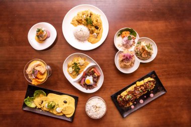 Set of typical Peruvian food dishes with known recipes, ceviches, lomo saltado, huancaina potatoes on wooden table