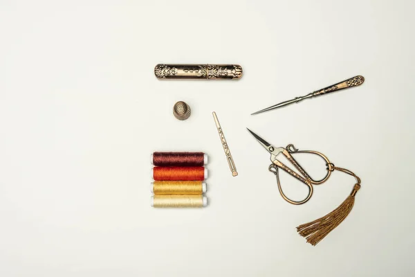一套老式风格的铜剪刀 顶针和缝纫饰物 以及各种颜色的线线轴 背景为浅白 — 图库照片