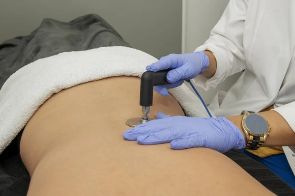 stock image Hands of a masseuse on the back of a patient applying a therapeutic massage with electrical equipment for dermo-aesthetic treatments