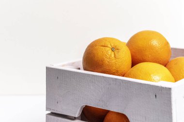 Beyaz arka planda meyve suyu yapmak için portakal dolu hafif ahşap meyve kutusu.