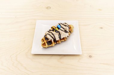 Çikolata soslu, kremalı ve küçük renkli çikolatalı waffle tarzı bir şekerleme.