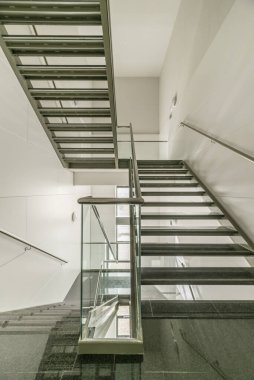 Parlak siyah granit basamakları ve inişleri olan ofis binasının metal merdivenleri.