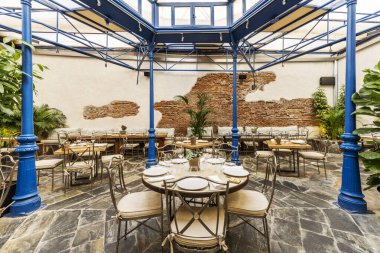 Terasta bir restoran yemek odası mavi boyanmış metal pergola ve kayrak döşemeli.