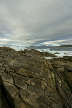 Sahilde fırtınalı bir gün dalgalı bir deniz büyük dalgalarla kayalıklara ulaşıyor.