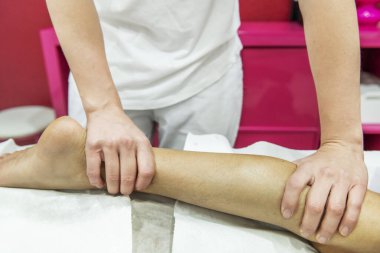 Hastanın bacağına baskı uygulayan bir masöz.