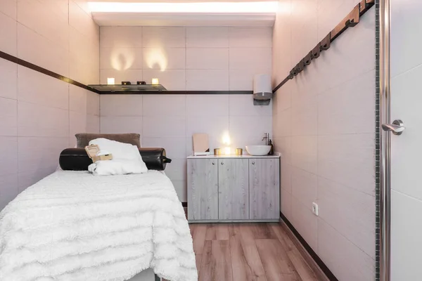 美容院的小木屋 配有按摩床 类似蜡烛的灯泡和木制餐具柜 — 图库照片