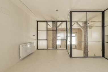 Eski ahşap kirişleri ve sütunları olan modern çatı katı, açıkta tuğla duvarlar, tek pencereli siyah metal çerçeveli bölmeler, pürüzsüz beyaz beton zemin