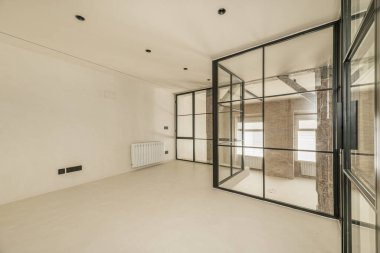 Parlak beyaz beton duvarları ve zemini olan bir çatı katının metal ve cam muhafazası.