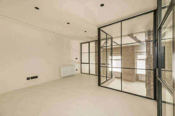 Metal and glass enclosure of a loft with polished white cement walls and floors
