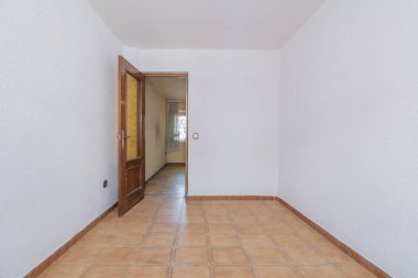 Eski moda taş kaplama döşemeleri ve turuncu camlı ahşap kapısı olan boş bir daire.