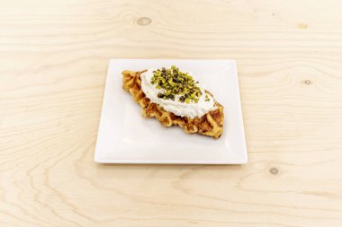 Bir sürü kremalı waffle keki ve tepesinde de fıstık.