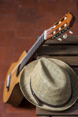 Tahta bir kutu ve hasır bir şapka üzerinde dinlenen bir gitar.