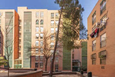 Ağaçların ve sokak mobilyalarının olduğu ortak bir alanda binaların cepheleri