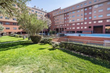 Ağaçların, çitlerin, çimlerin, mobilyaların ve yüzme havuzlarının bulunduğu ortak bir alandaki binaların iç avlusunun cepheleri