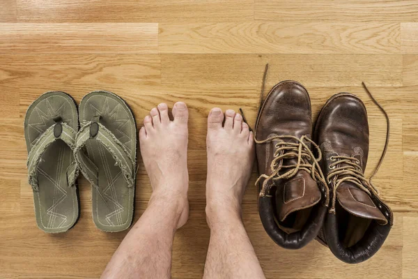 Some barefoot male feet hesitating between sandals or boots