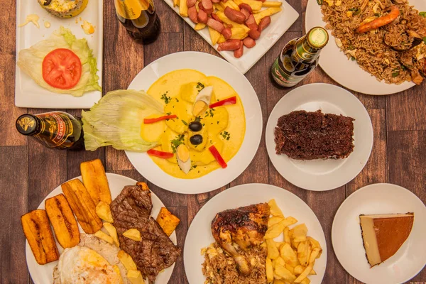 stock image A set of Peruvian food dishes with huancaina potatoes in the center, a quesillo, steaks with rice and plantains, arros chaufa and drinks