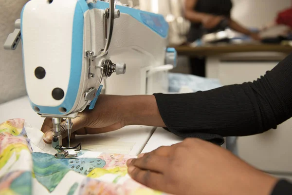 縫製工場で工業用ミシンを使用している黒髪の女性の手 — ストック写真