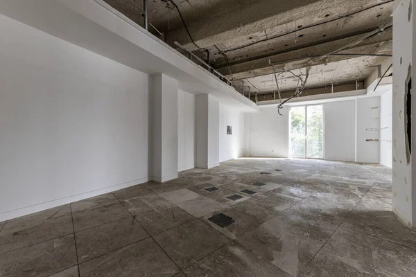 An empty office with all the materials removed, raised floors and cables hung to make a new renovation