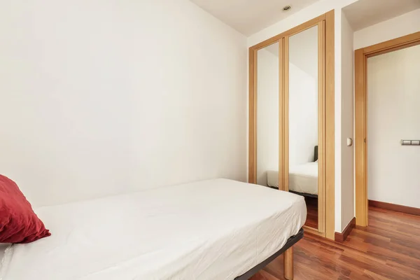 寝室のない小さなベッドと鏡で覆われたスライドドア付きのワードローブの部屋 — ストック写真