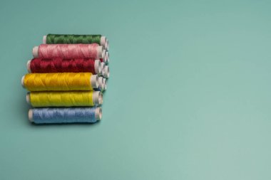 Turkuaz mavi bir yüzeye dizilmiş çok renkli dikiş ipliği makaraları
