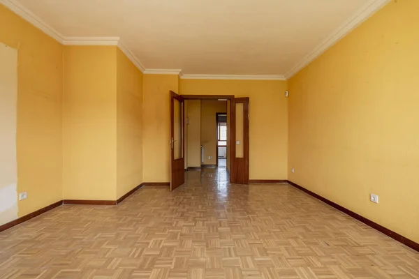 stock image A large empty room with oak parquet floors placed in a checkerboard pattern and a sapele wood double access door with windows