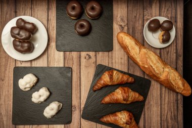 Basit çikolata şekerli bir tabak, tereyağlı kruvasan ve bir somun ekmek.