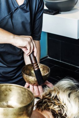 Tibet kâsesinde ahşap bir bagetle ses çıkaran bir masöz.