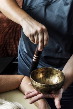 Tibet kâsesine hastanın rahatı için konsantre kuvvet uygulayan bir masöz.