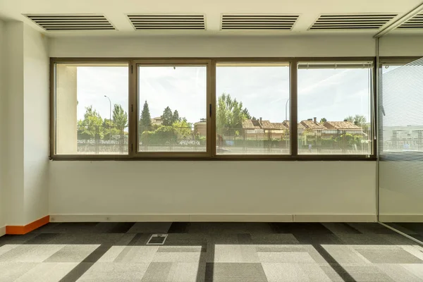 stock image empty offices with separate offices with glass partitions, large windows with unobstructed views of other buildings, technical ceilings and gray carpeted floor