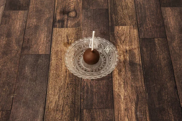 stock image A chocolate ball with a stick to hold on a small glass plate