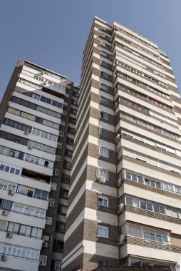 Kahverengi tuğlalı ve yatay alçı bantlı uzun bir apartman dairesi.